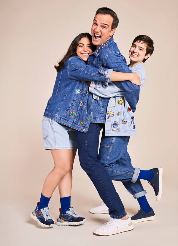 Tadeu Schmidt em campanha com as duas filhas. Eles se abraçam vestidos de jeans - Metrópoles