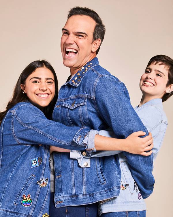 Tadeu Schmidt em campanha com as duas filhas. Eles se abraçam vestidos de jeans - Metrópoles