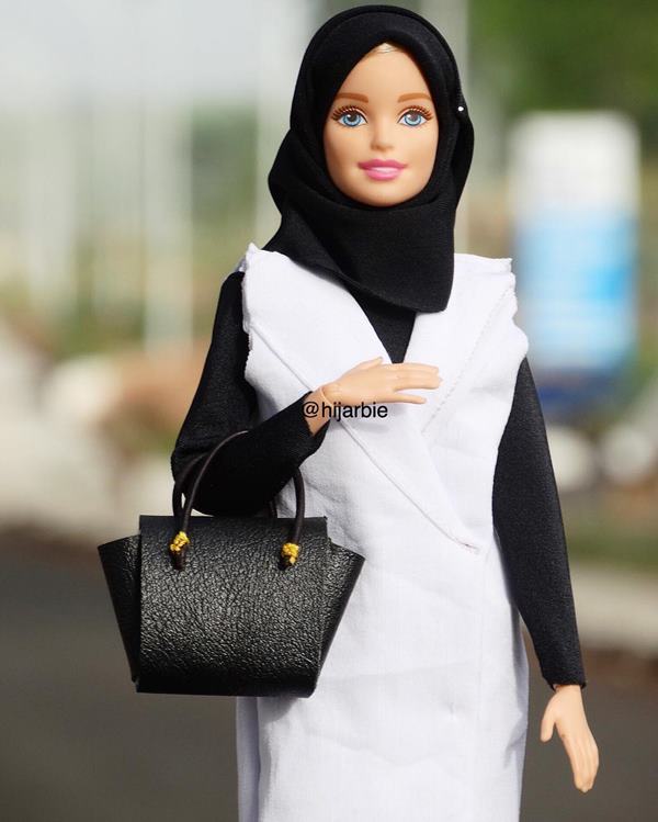 Barbie com hijab posa para a foto. Ela está segurando uma bolsa em um dos braços - Metrópoles