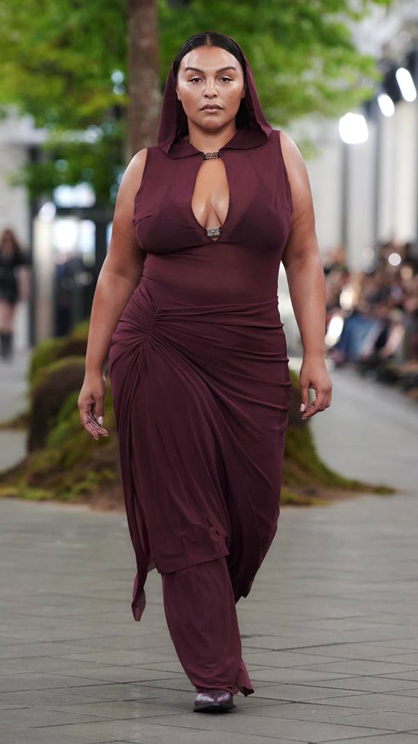 Modelo usa vestido marrom com decote em passarela de moda - Metróples