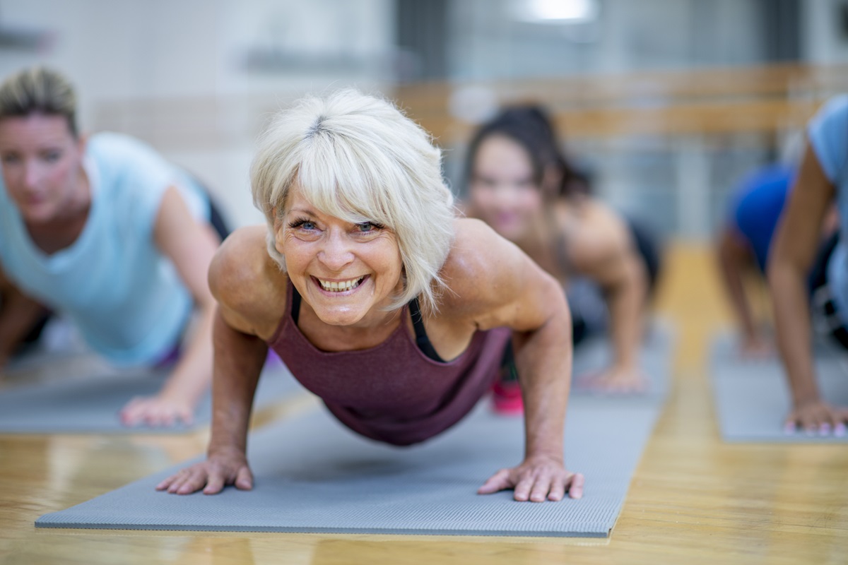 Foto colorida de mulher branca e idosa fazendo o exercício de prancha em um tapete - Metrópoles