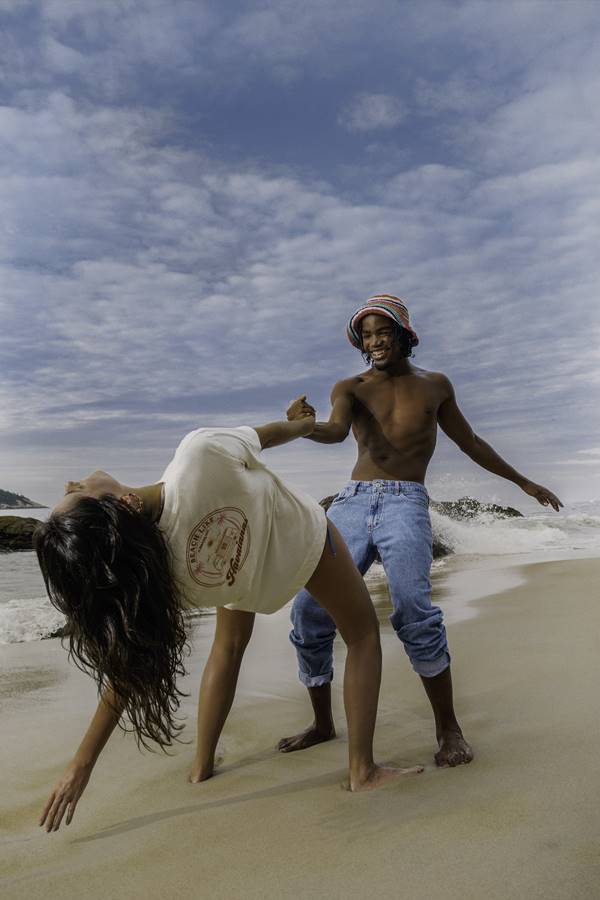 Campanha da Havaianas: um homem e uma mulher brincam de mãos dadas na praia - Metrópoles