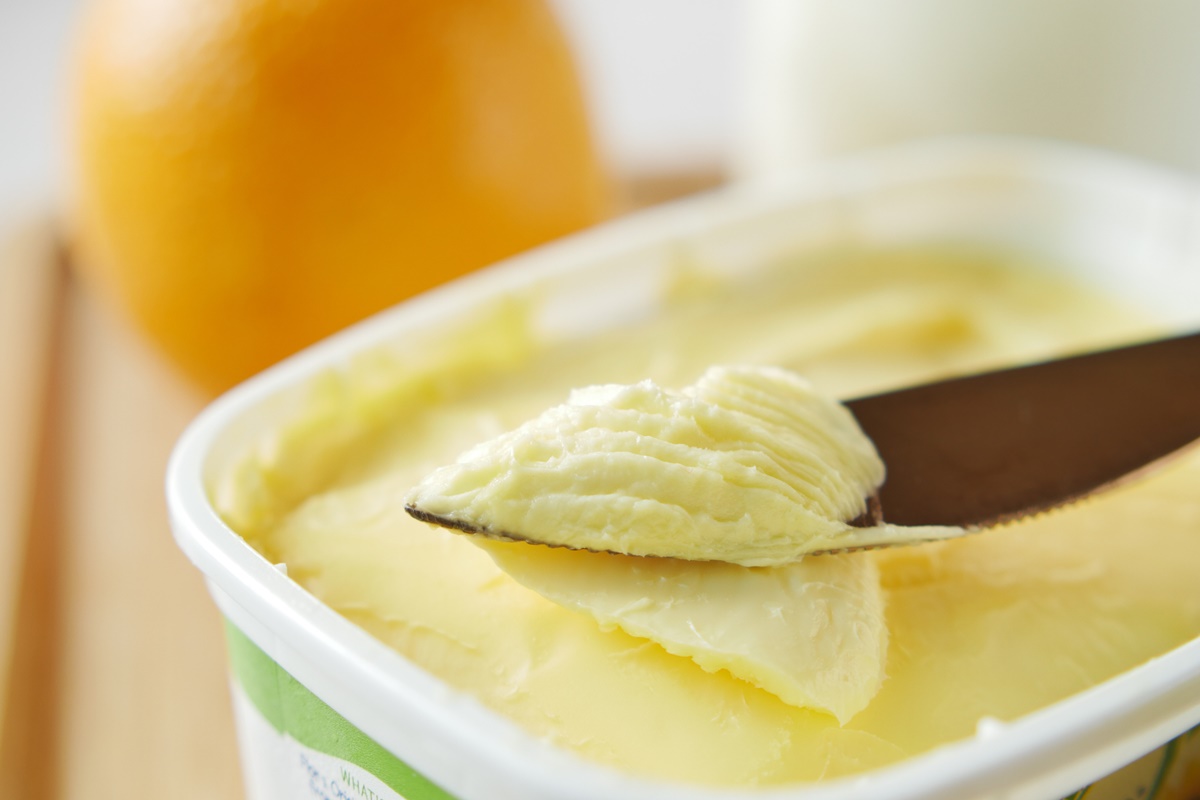 Foto colorida de faca raspando margarina dentro de uma vasilha - Metrópoles
