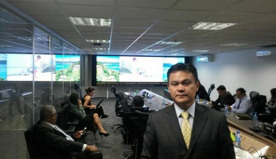 Imagem colorida mostra o promotor Lincoln Gakiya, do Gaeco, em uma sala cheia de pessoas olhando para uma tela - Metrpoles