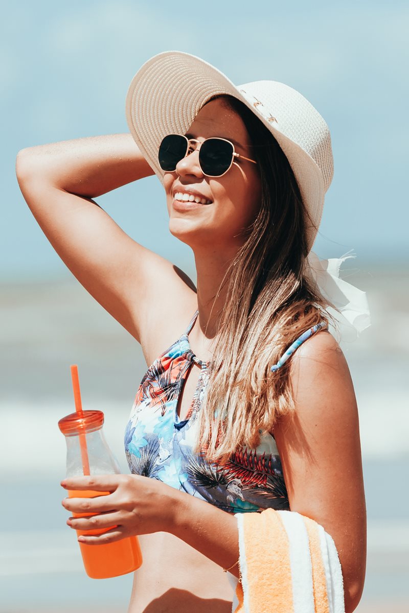 Foto colorida de mulher parda com óculos de sol e chapéu - Metrópoles