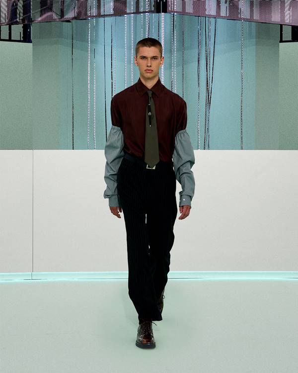 Na passarela de moda, modelo usa look com camisa social de mangas bufantes, calça de alfaiataria e gravata - Metrópoles