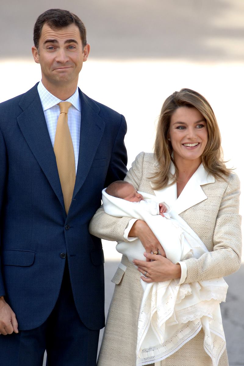 Foto colorida de homem pardo, com terno, ao lado de mulher parda, com roupas brancas. Ela segura um bebê no colo - Metrópoles