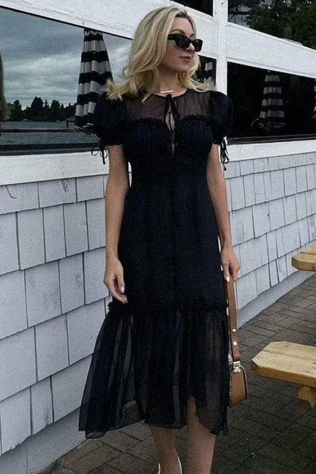 Foto colorida de uma mulher com vestido preto - Metrópoles