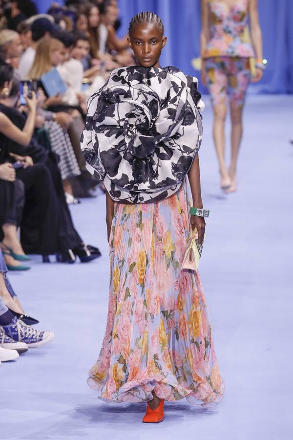 Na passarela de moda, modelo usa look com mix de estampas em top tridimensional e saia plissada com flores - Metrópoles