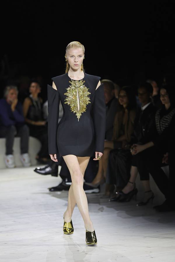 Vestido preto com detalhes dourados ao centro em passarela de moda - Metrópoles