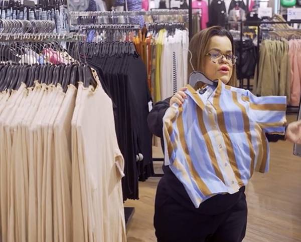 Em loja, mulher com nanismo segura camisa listrada em cabide - Metrópoles