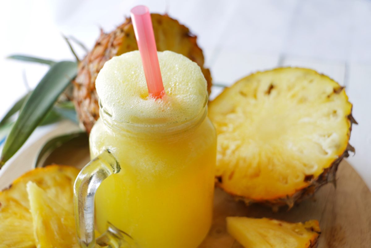 Foto ilustrativa de copo com suco de abacaxi contra ressaca e fruta ao lado - Metrópoles