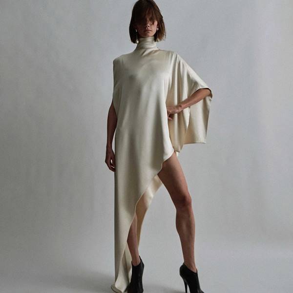 Na coleção de estreia da marca própria de Phoebe Philo, modelo usa vestido creme acetinado e assimétrico com gola alta - Metrópoles