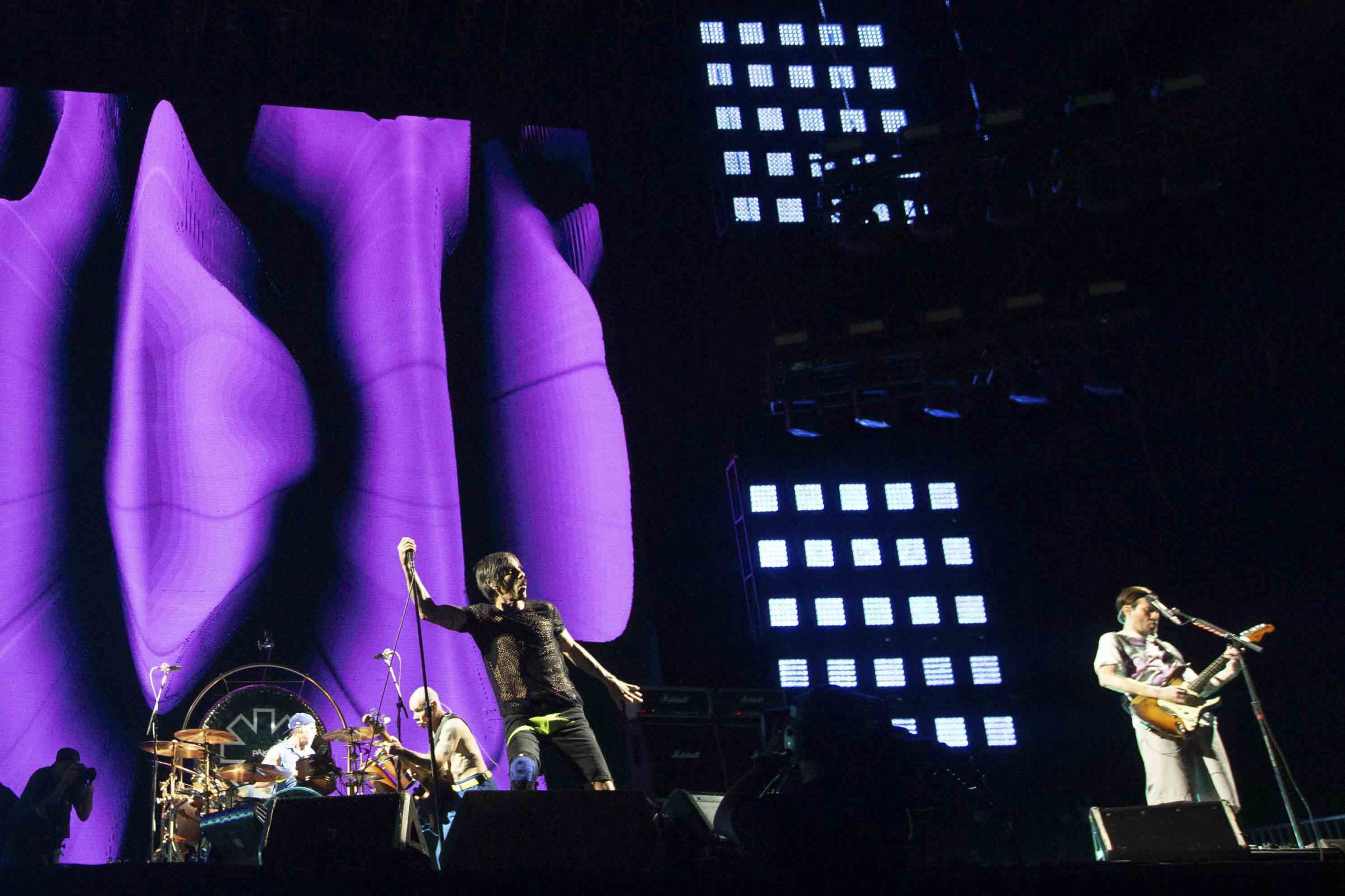 Foto colorida de Anthony Kiedis (voz), Flea (baixo) e Chad Smith (bateria) em turnê de Red Hot Chili Peppers - Metrópoles