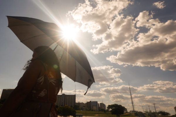 Observatório Imagem colorida de mulher se protegendo do sol com o guarda-chuva calor altas temperaturas calorão - Metrópoles
