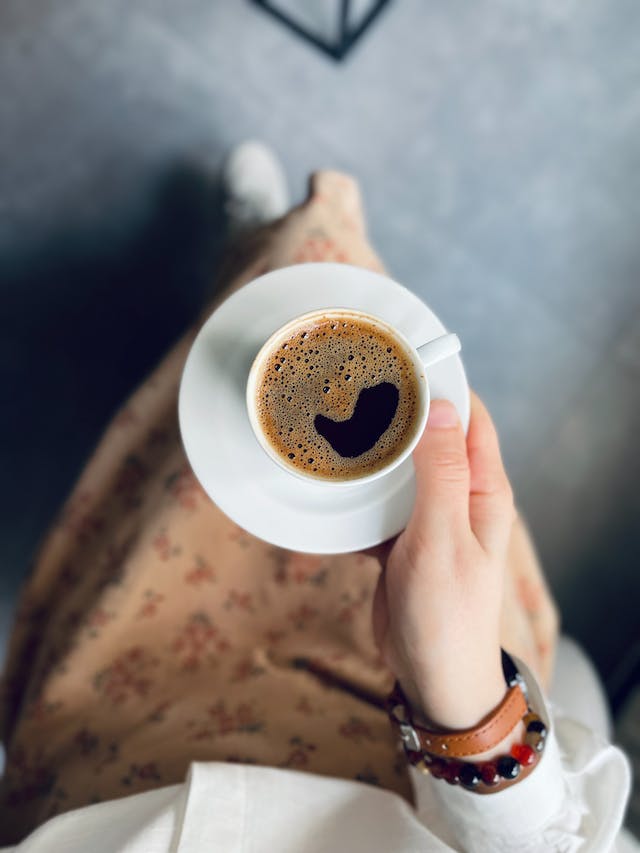 Mão de mulher segurando pires e xícara de café - Metrópoles