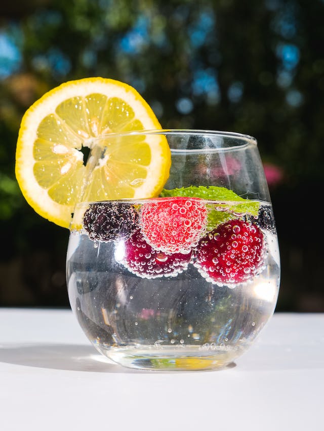 Copo de vidro com água e frutas dentro - Metrópoles