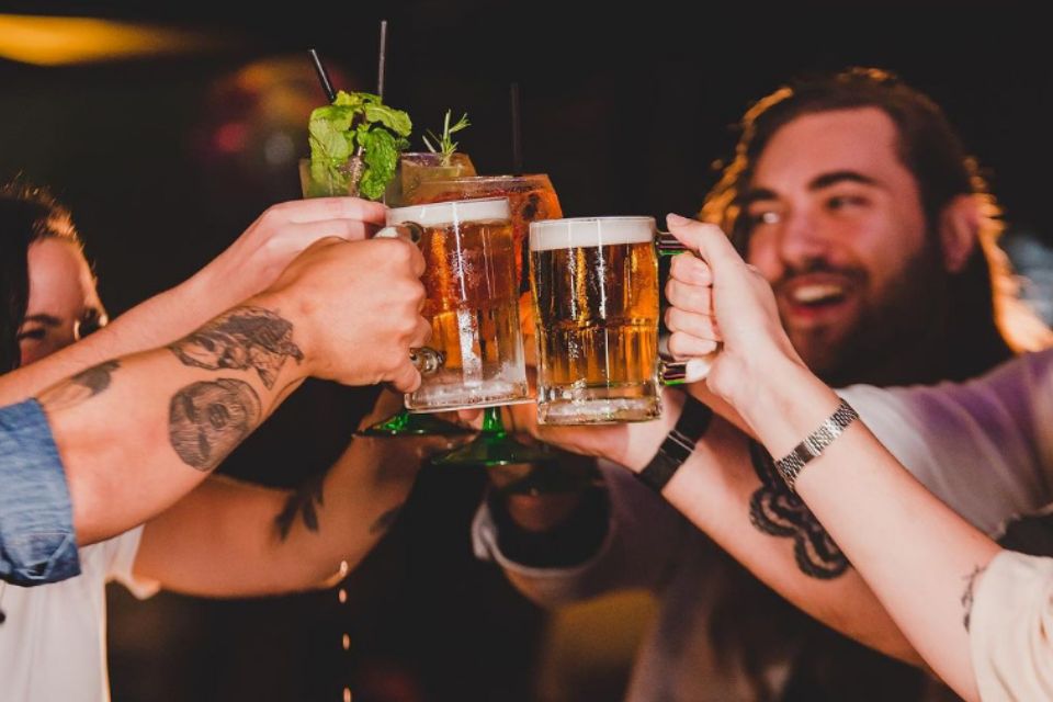 Foto colorida de pessoas segurando cerveja - Metrópoles