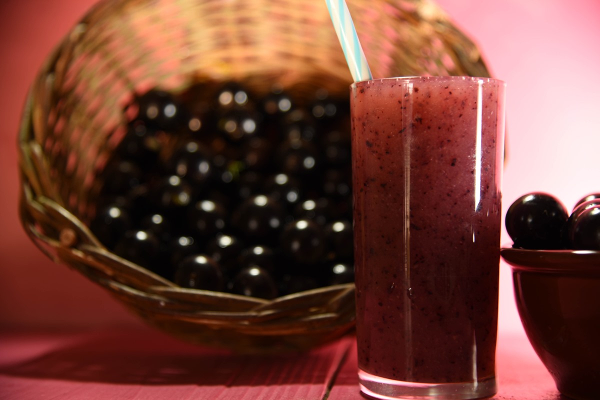 Foto colorida de bacia com jabuticabas e um copo de suco da fruta - Metrópoles