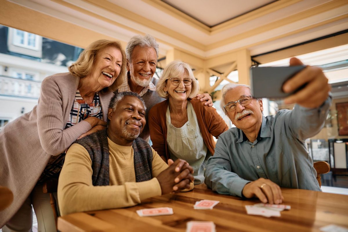 Foto mostra grupo de cinco idosos juntos tirando selfie. Envelhecendo bem