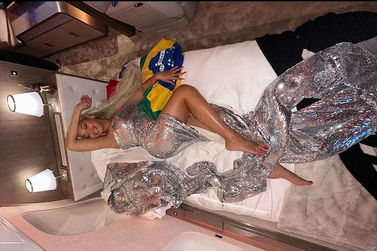 Foto de mulher deitada em cama perto da bandeira do Brasil - Metrópoles