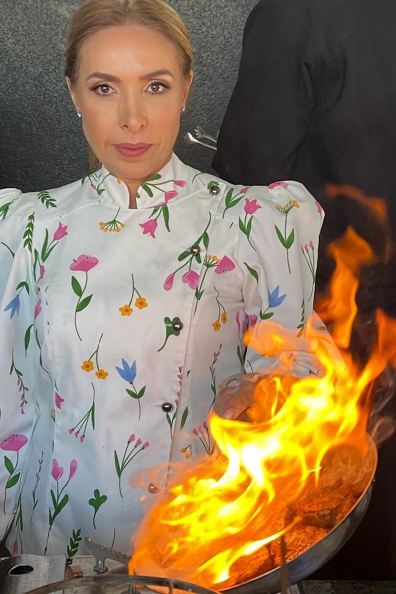 Foto de mulher com vestido estampado flambando um alimento - Metrópoles