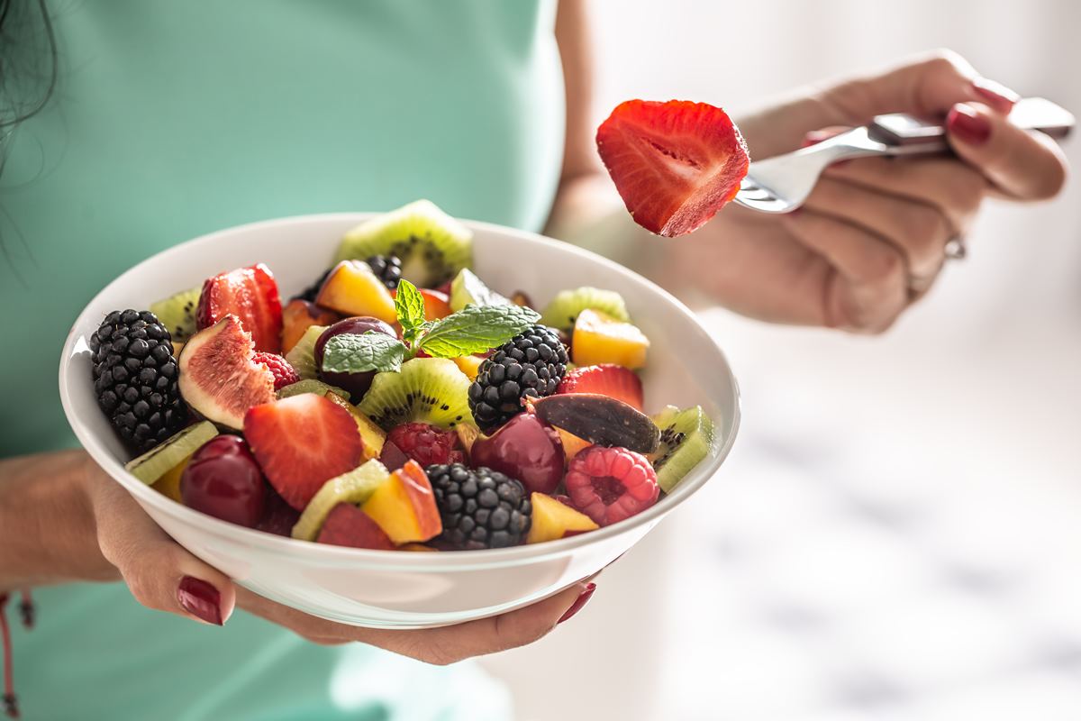 Uma mulher segura uma tigela branca com salada de frutas rica em vitaminas e fibras - Metrópoles