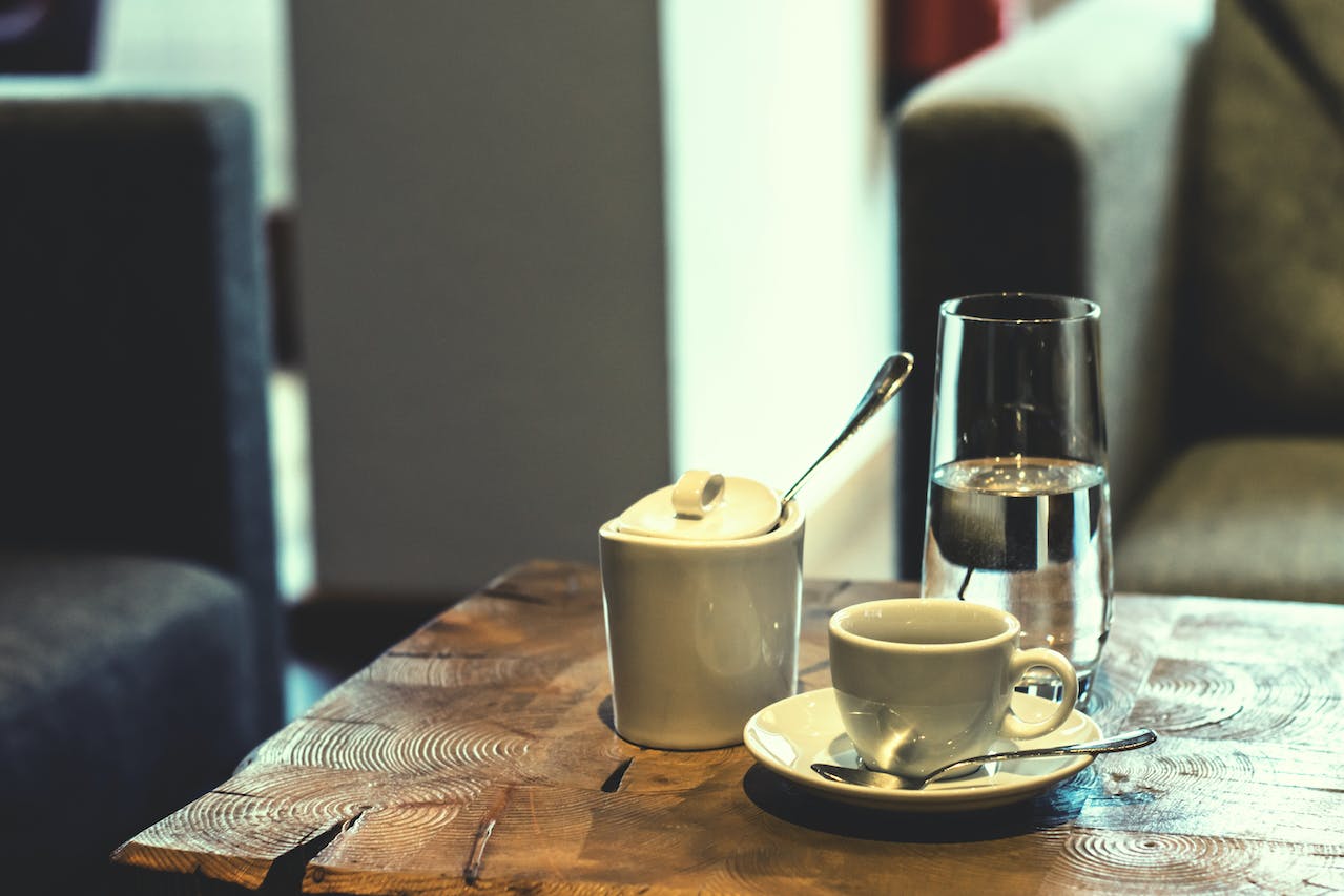 Mesa com xícara de café, um copo de água e um açucareiro - Metrópoles