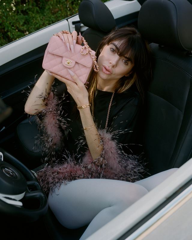 Sentada em banco de carro, mulher exibe bolsa rosa da Chanel - Metrópoles