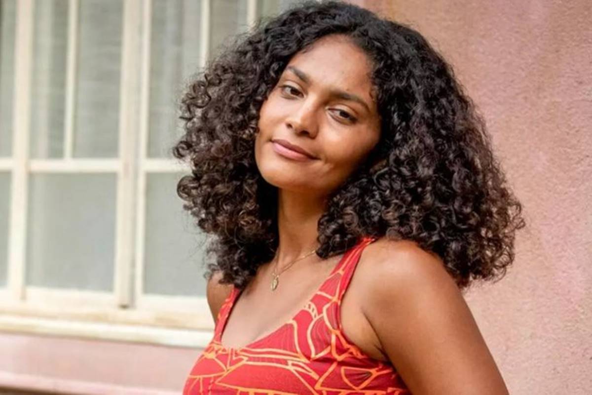 Foto de uma mulher negra, do cabelo preto e cacheado, usando uma regata vermelha - Metrópoles