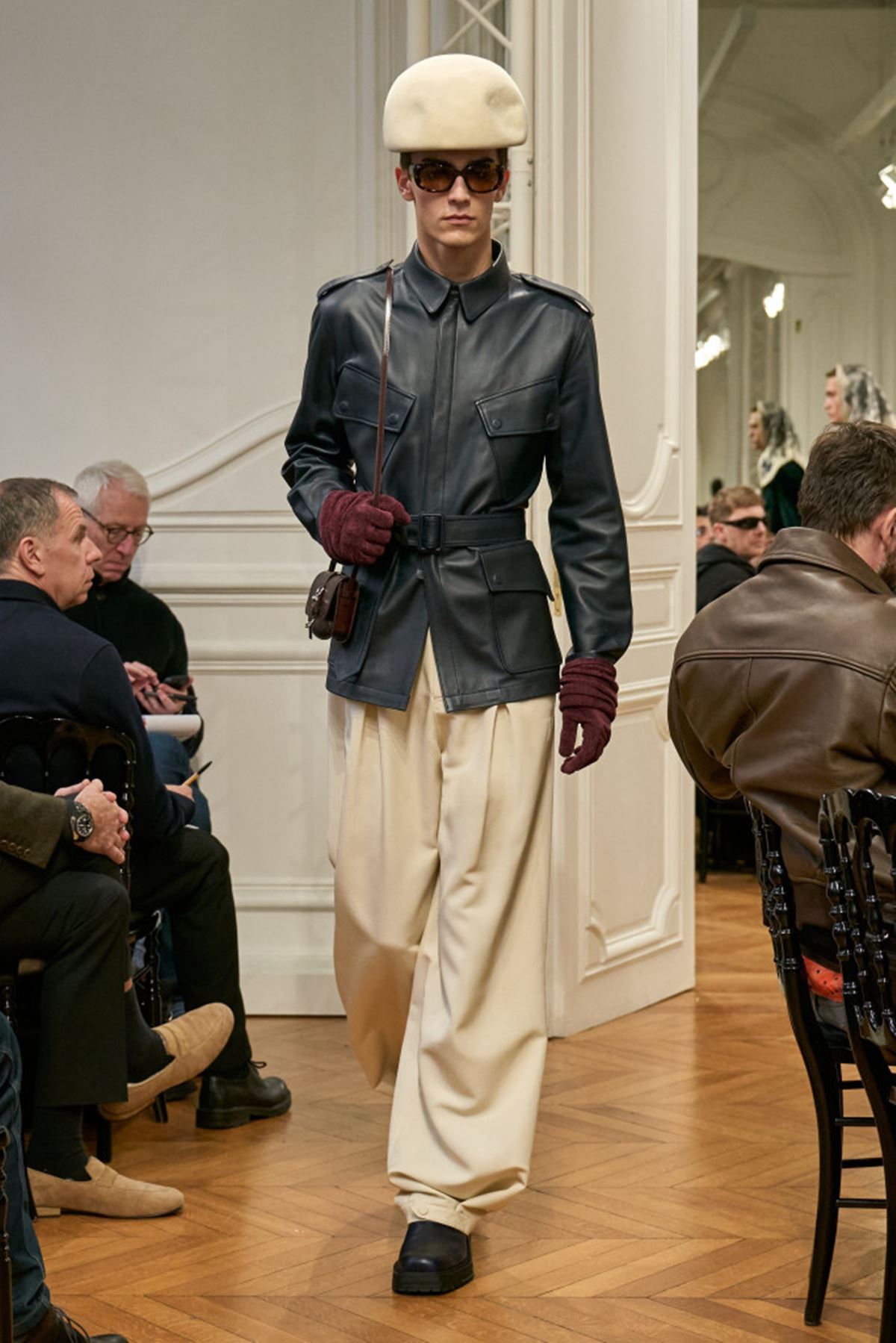 Modelo usando boina, casaco de couro e calça de alfaiataria na passarela - Metrópoles
