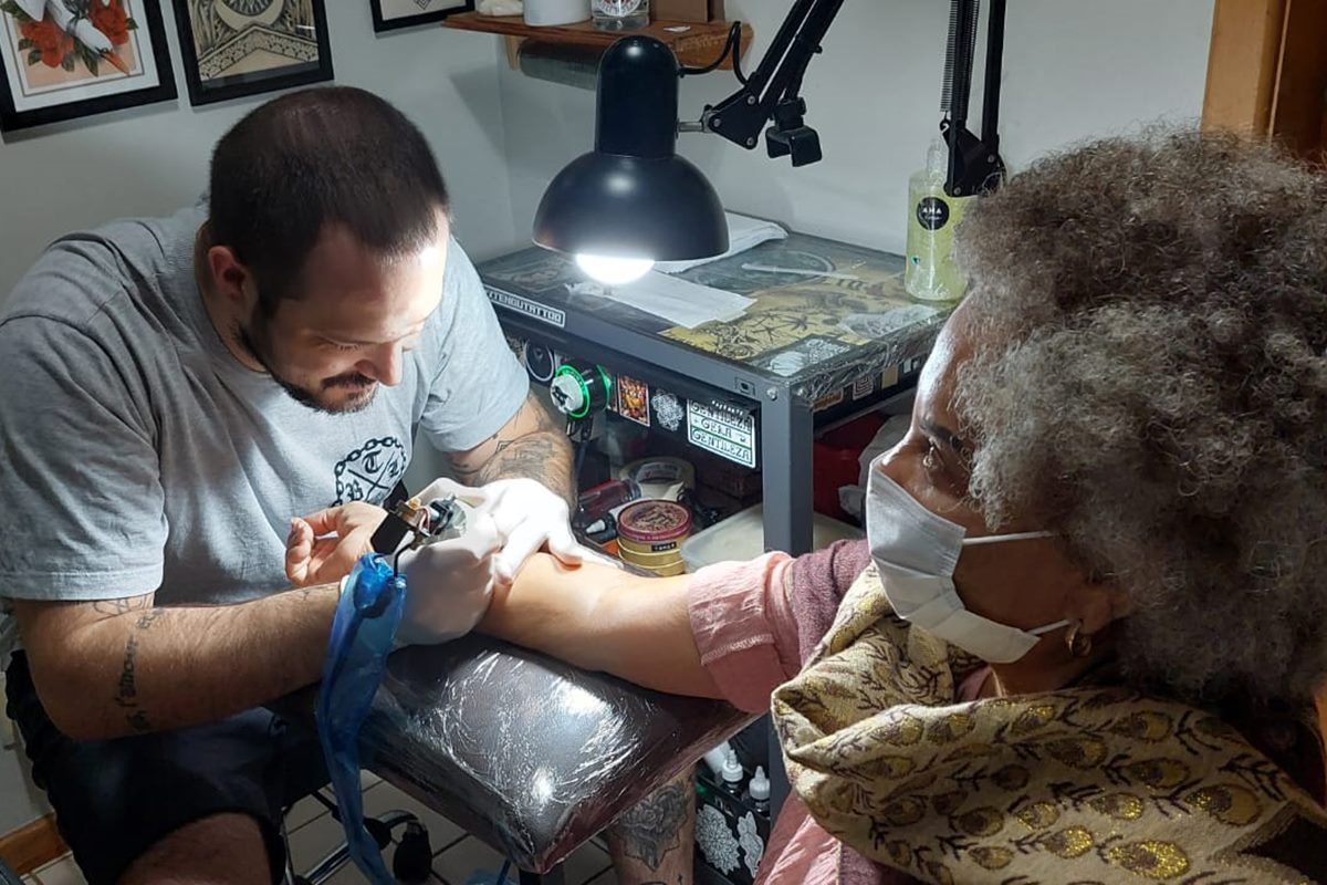 Homem tatuando o braço de uma mulher 