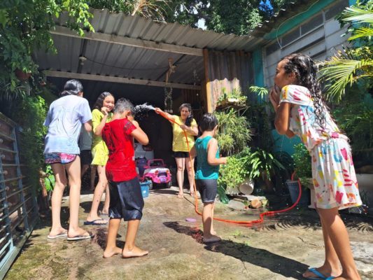imagem colorida mostra crianças brincando de banho de mangueira em casa na zona leste da cidade - metrópoles