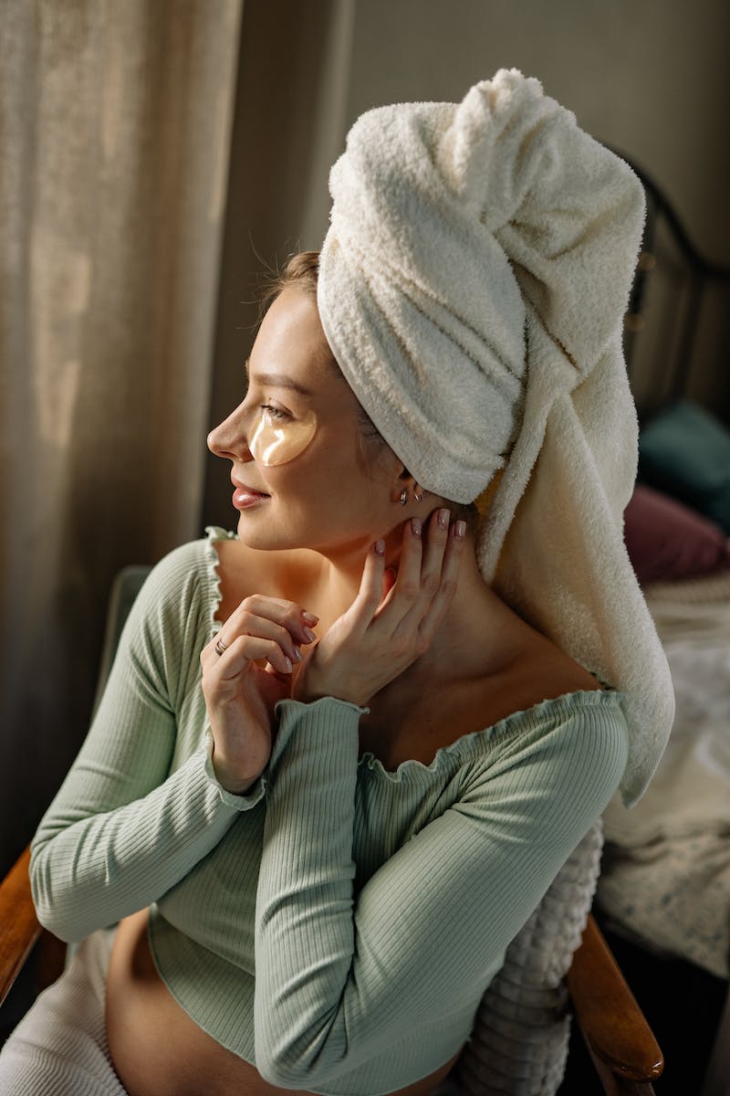 Jovem mulher com toalha no cabelo olhando pela janela