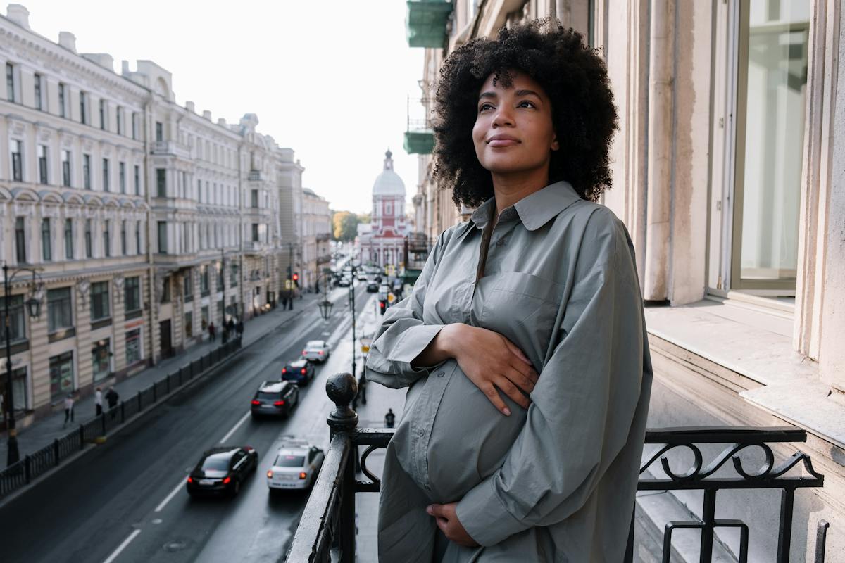Jovem mulher negra em varanda de apartamento olhando para a rua - Metrópoles
