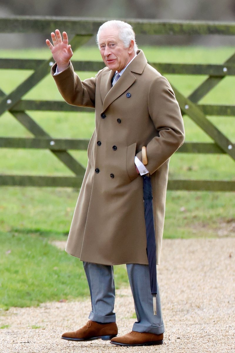 Foto do rei Charles, um homem idoso, com casaco marrom, acenando. Ele está caminhando - Metrópoles