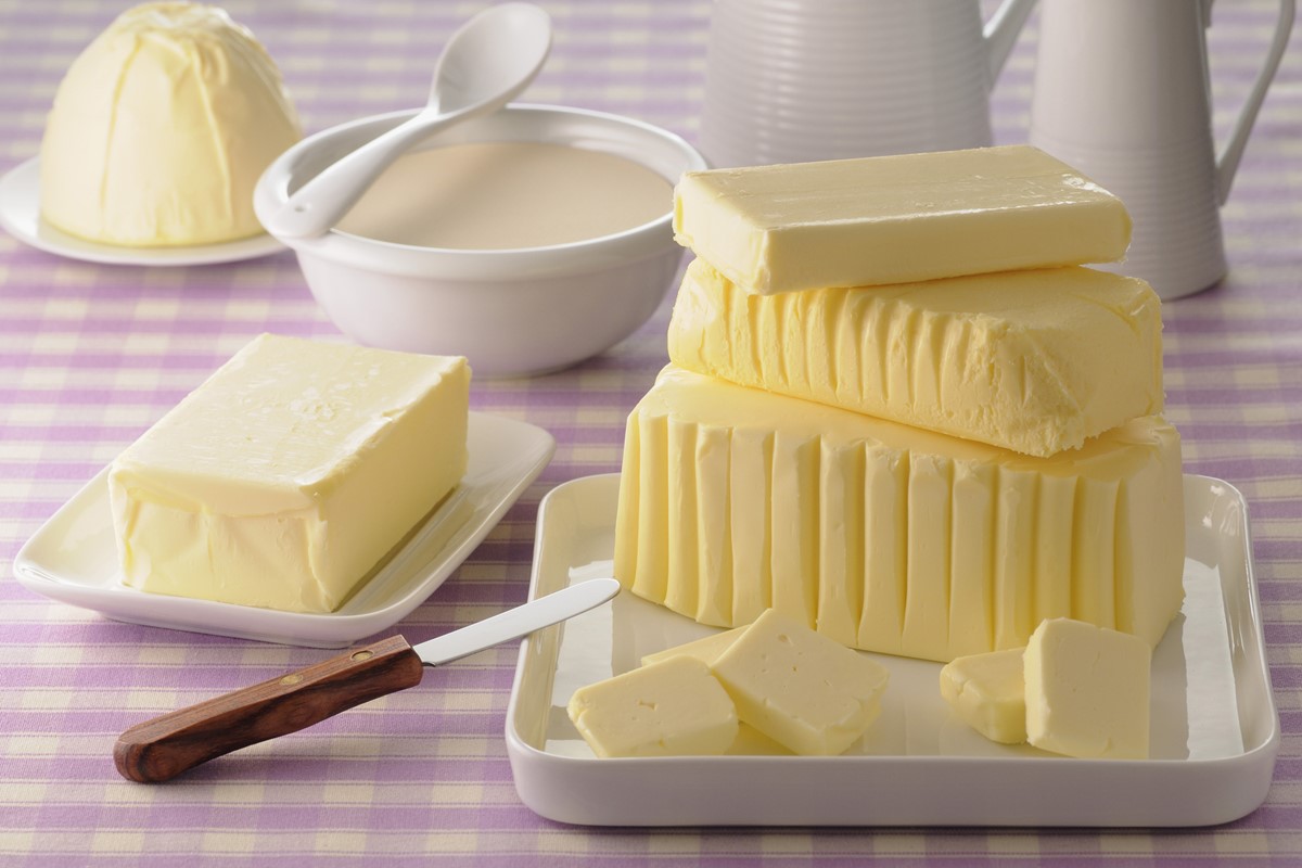 Foto de manteiga em diversos formatos sobre pratos, que estão em cima de uma toalha xadrez - Metrópoles