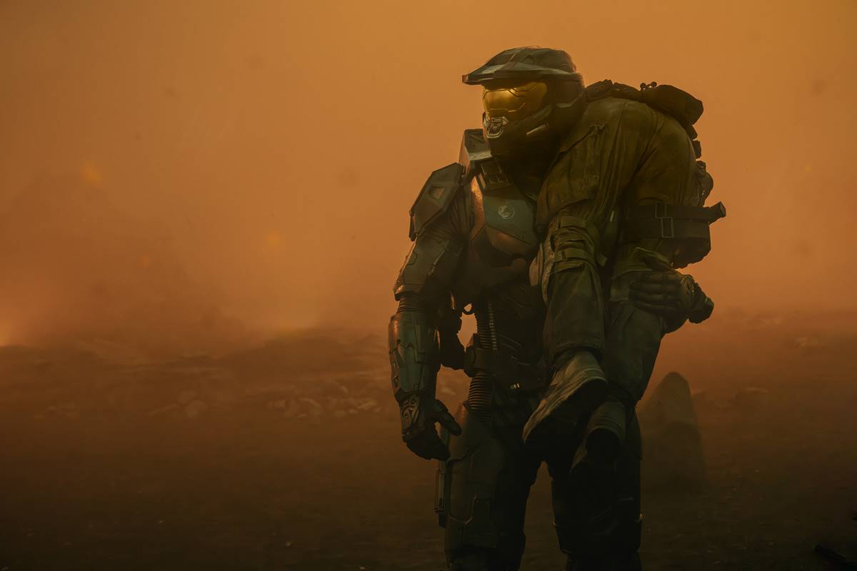 Foto colorida da segunda temporada da série Halo. Imagem mostra um homem com outra pessoa nas costas - Metrópoles