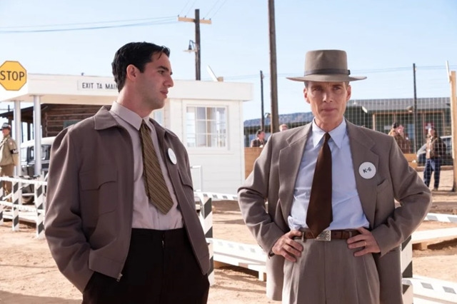 Trecho do filme Oppenheimer. Na cena, dois homens usam looks com gravata. Um deles está de chapéu - Metrópoles