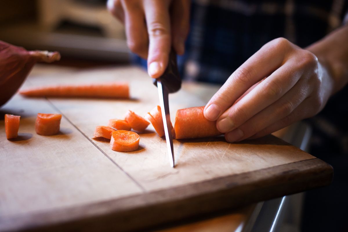 Pessoa cortando a cenoura em rodelas