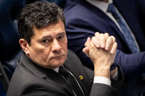 Imagem colorida de Sergio Moro de terno, em plenário, com dedos cruzados julgamento