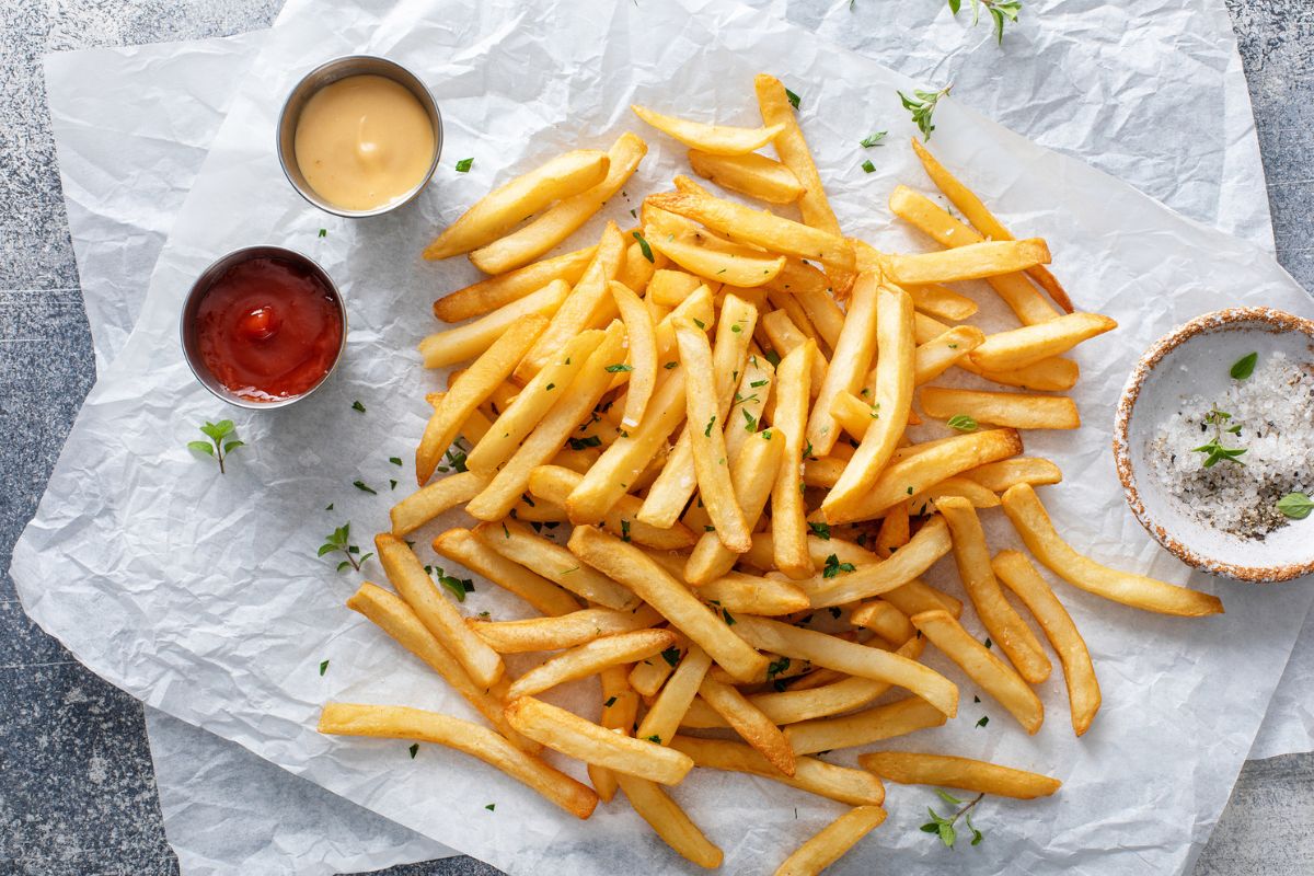 superfície clara com batata fritas e dois potinhos de ketchup