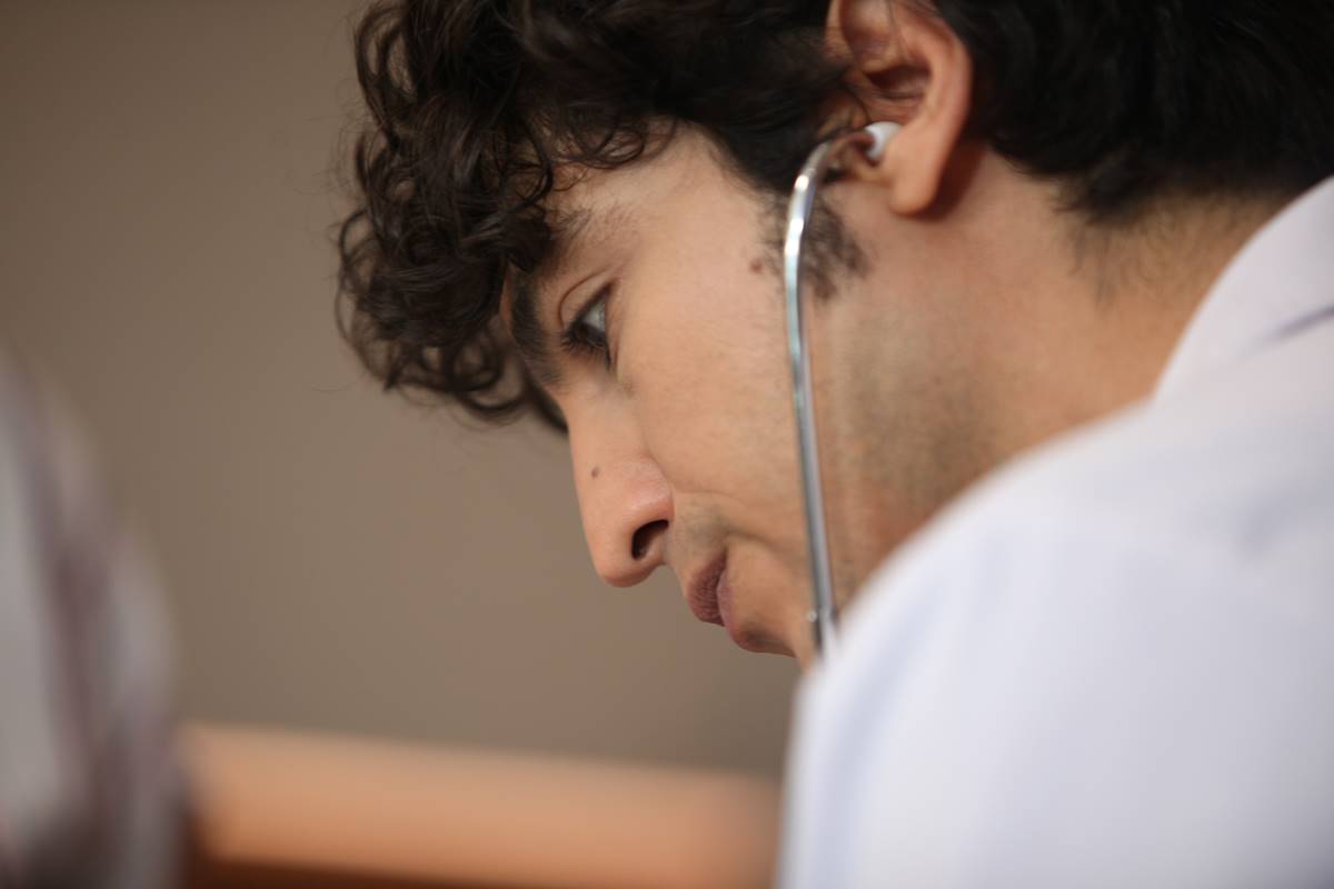 foto colorida de rosto de homem jovem com estetoscópio no ouvido - metrópoles