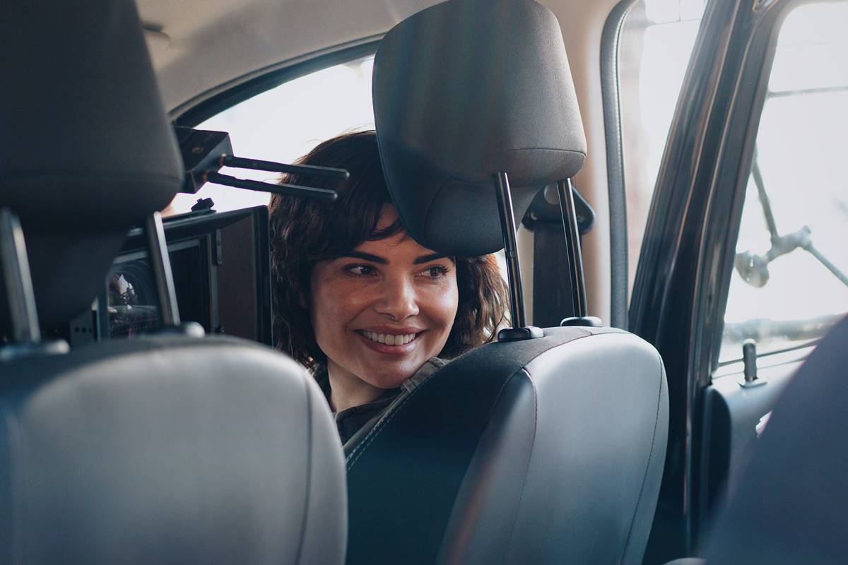Foto mostra mulher em carro, sorrindo e olhando para trás - Metrópoles