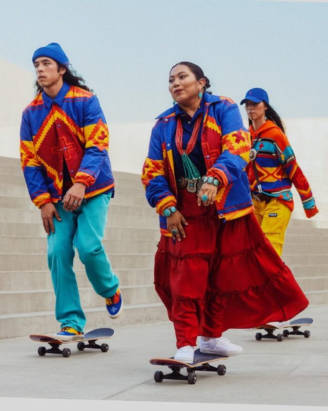 Na imagem, três modelos andam de skate vestindo as roupas da coleção. Em destaque estão as cores azul, vemerlho, amarelo e laranja.