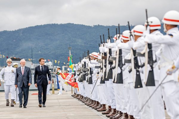 Imagem colorida mostra presidentes Lula e Emmanuel Macron em caminhada em meio a uma fila de militares em Itaguaí (RJ) - Metrópoles