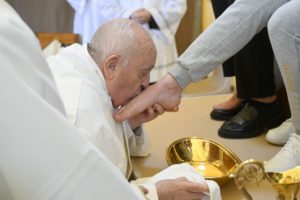 Foto colorida do papa Francisco beijando o pé de uma mulher - Metrópoles