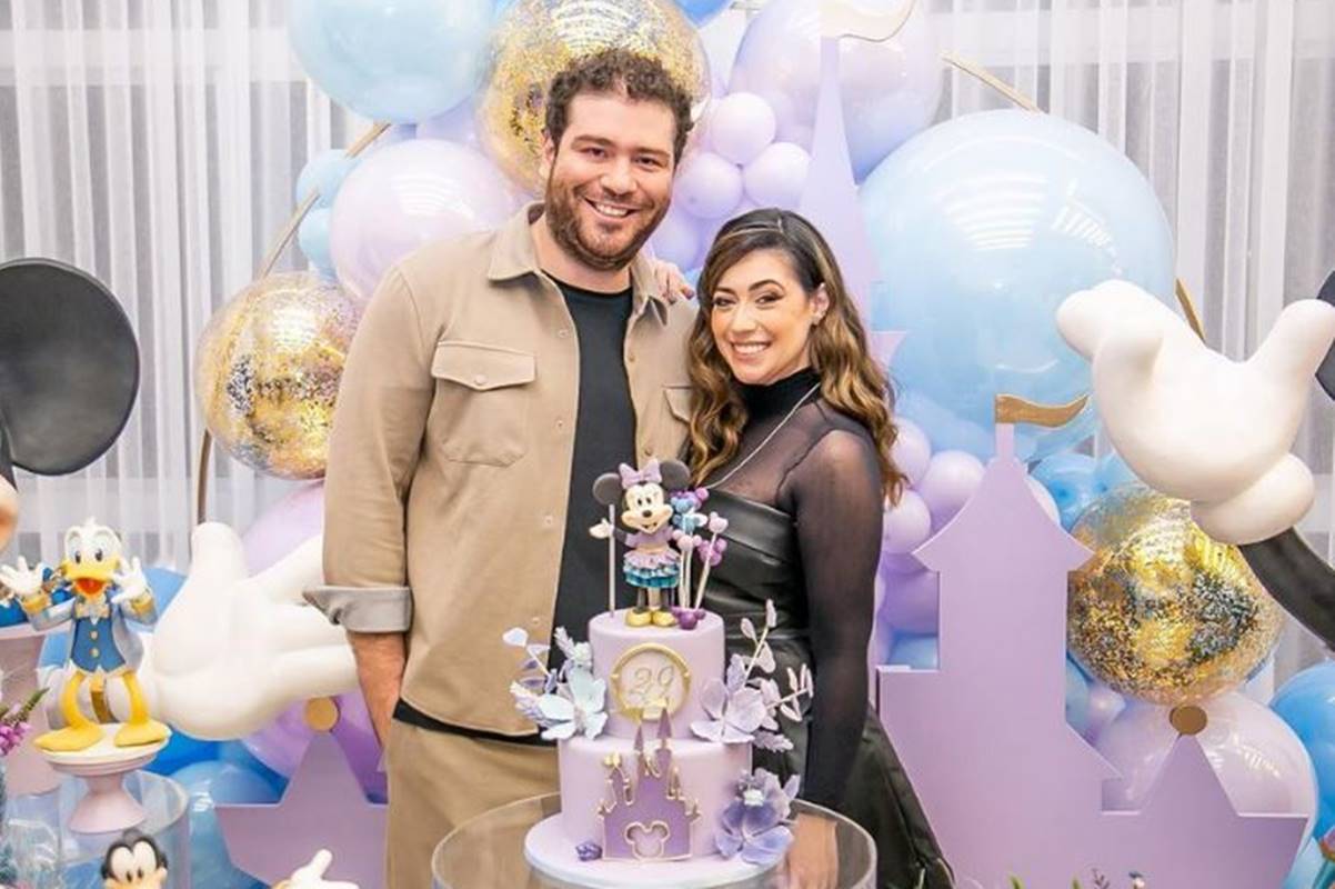 foto colorida de homem alto sorrindo abraçado em mulher mais baixa em festa de aniversario - metrópoles