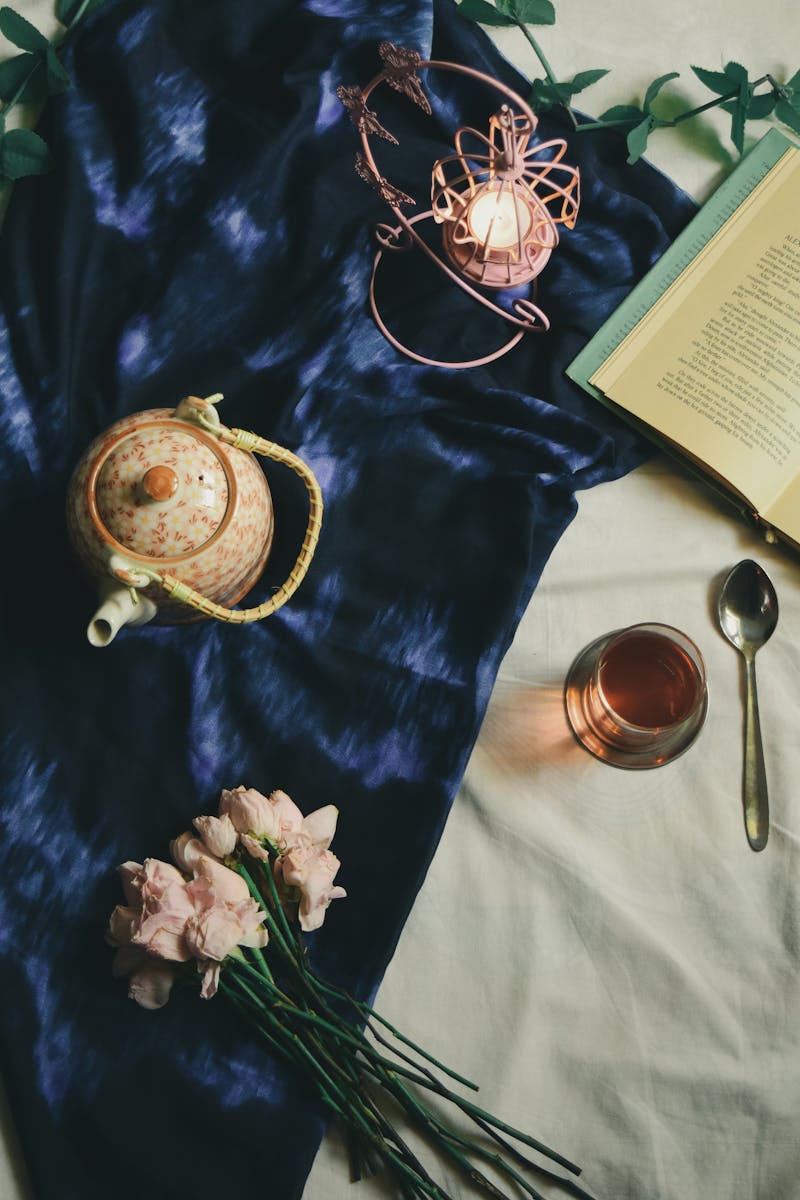 Bule e xícara de chá com colher, flores e um livro sob a cama - Metrópoles