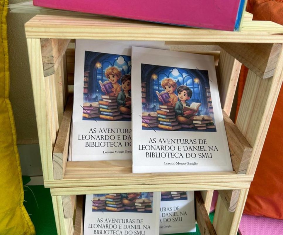 Foto colorida de livros de capa colorida dentro de caixa de madeira aberta
